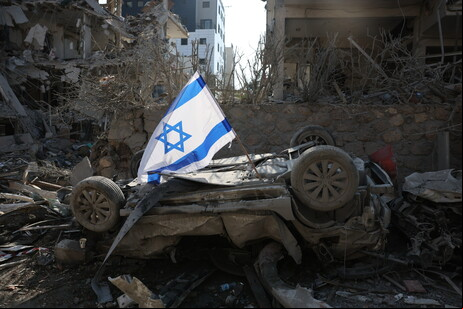 Uma bandeira israelense colocada em um carro danificado pela explosão de um míssil balístico do Irã